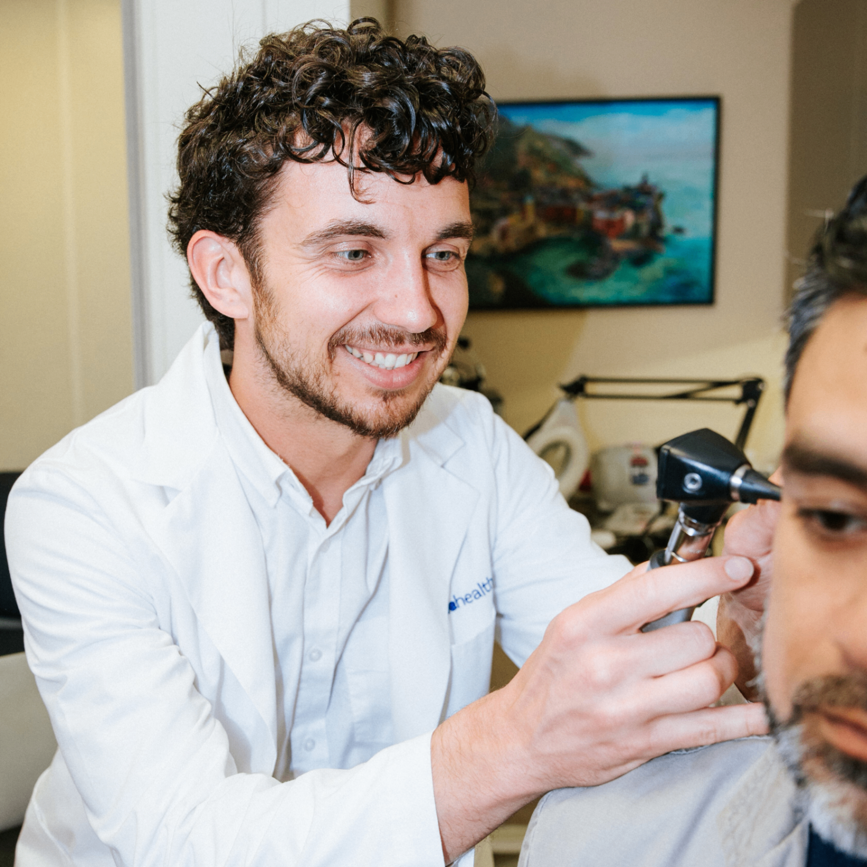 Ben examining a patient's ear with an otoscope