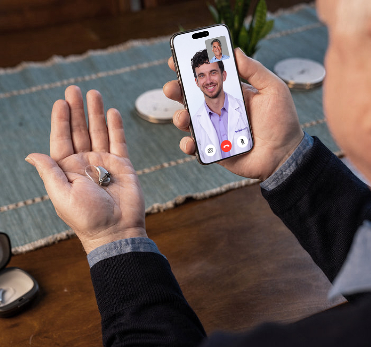 Patient on a telehealth call with Ben, holding a hearing aid